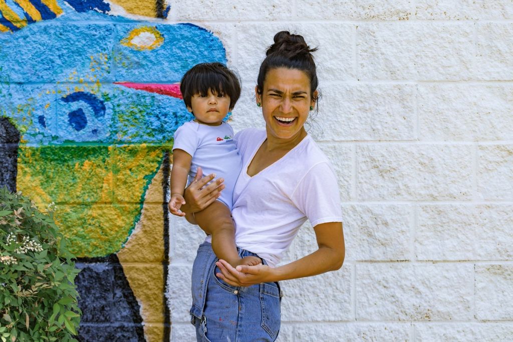 Mecklenburg artist Irisol Gonzalez (pictured holding the child of a community member). Photo by Ernesto Moreno.