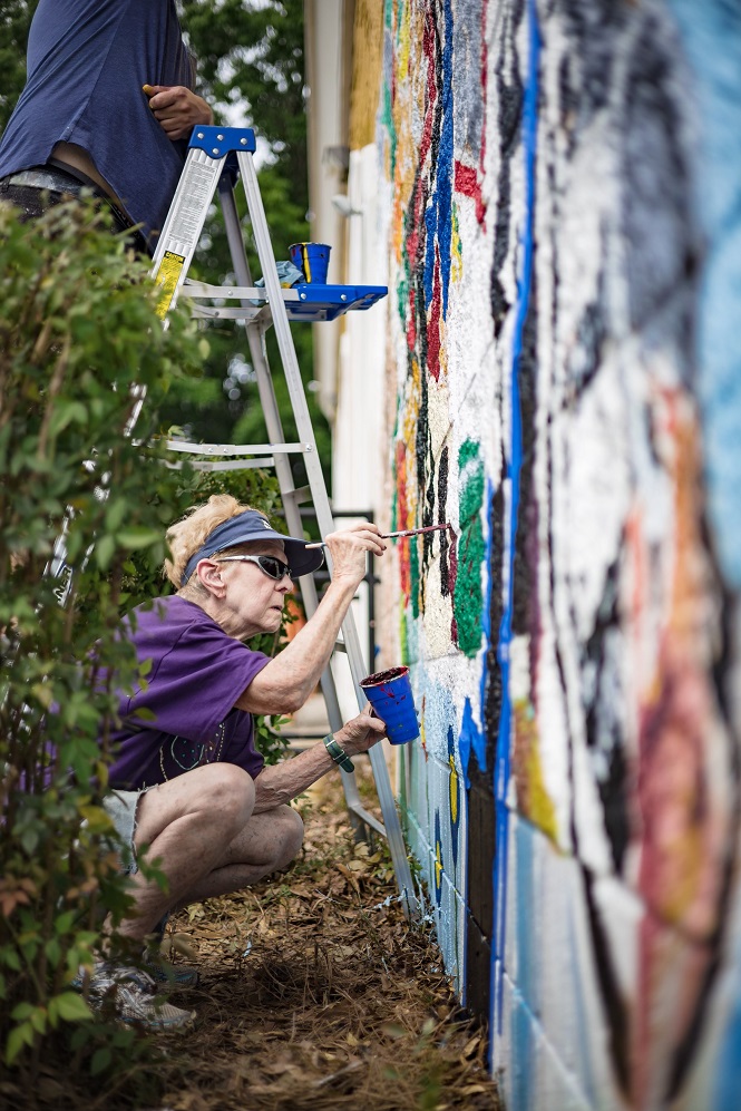 A community member helping paint a community mural at Compare Foods in East Charlotte. Photo by Ernesto Moreno.