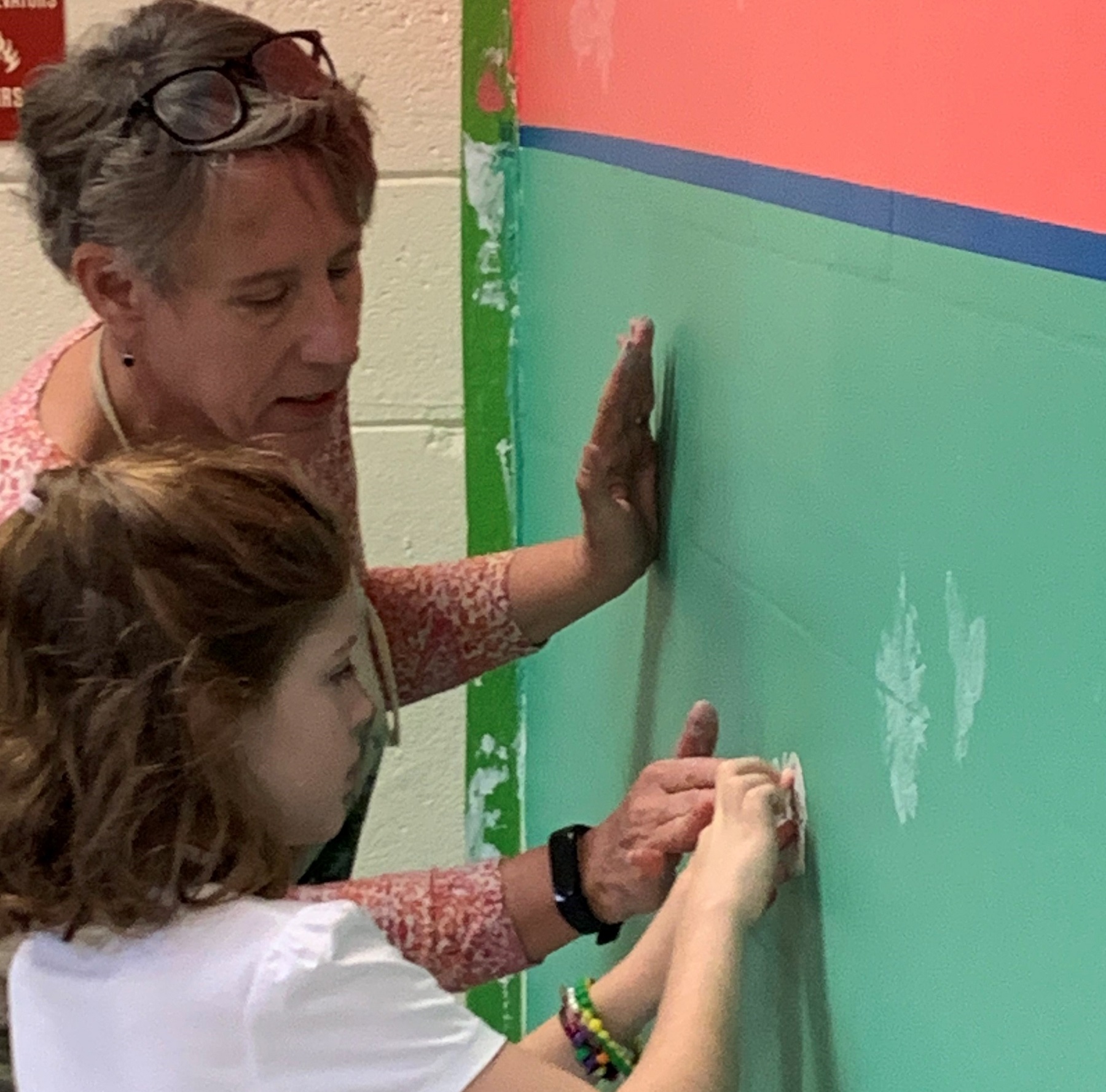 Teaching artist Amy St. Aubin works with a student at Endhaven Elementary on the mural the school is creating. 