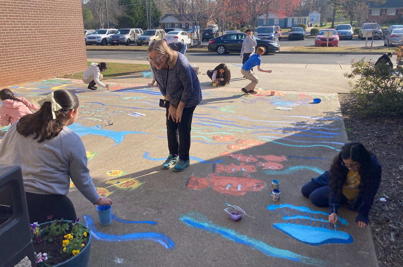 Devonshire Elementary Art teacher Jean Mooney checks in on her students while they paint final details on their entryway mural with Amy St. Aubin. 