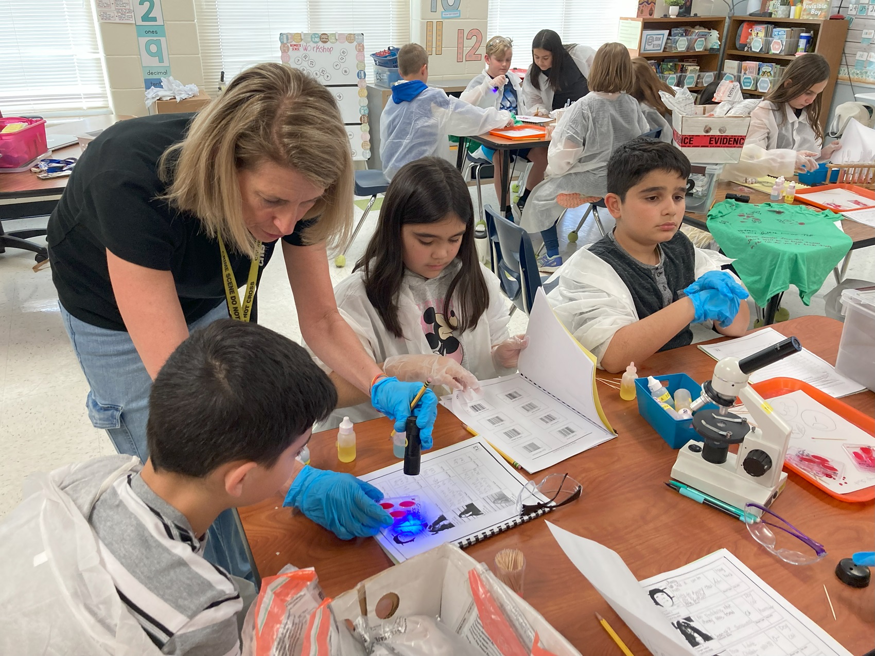 Patricia Stegura confers with an Elon Park Elementary student as he tests a blood sample during the final case of the day in her forensics workshop. 